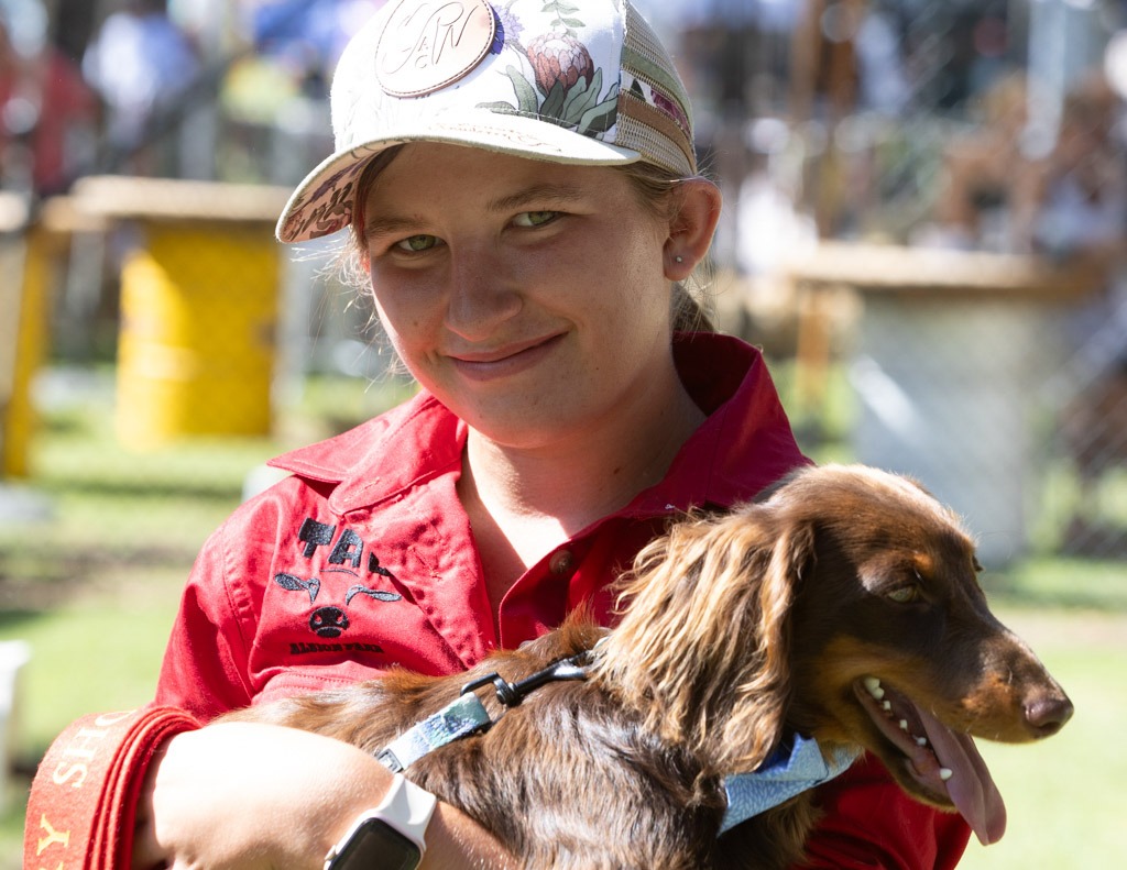 A boy in a cap holding a dachshund