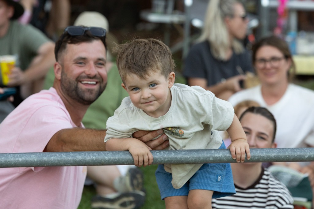 A father and son leaning on the arena rail