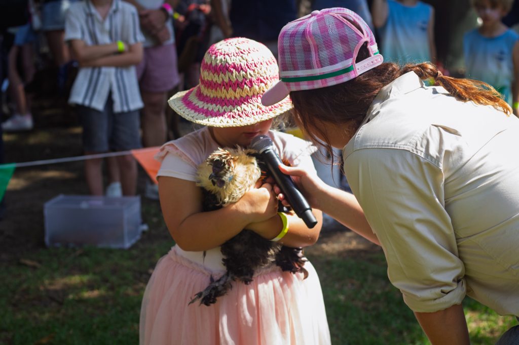 A girl holding her guinea pig up to the microphone