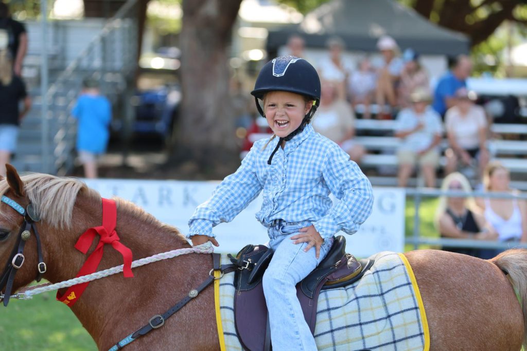 A smiling boy riding a pony