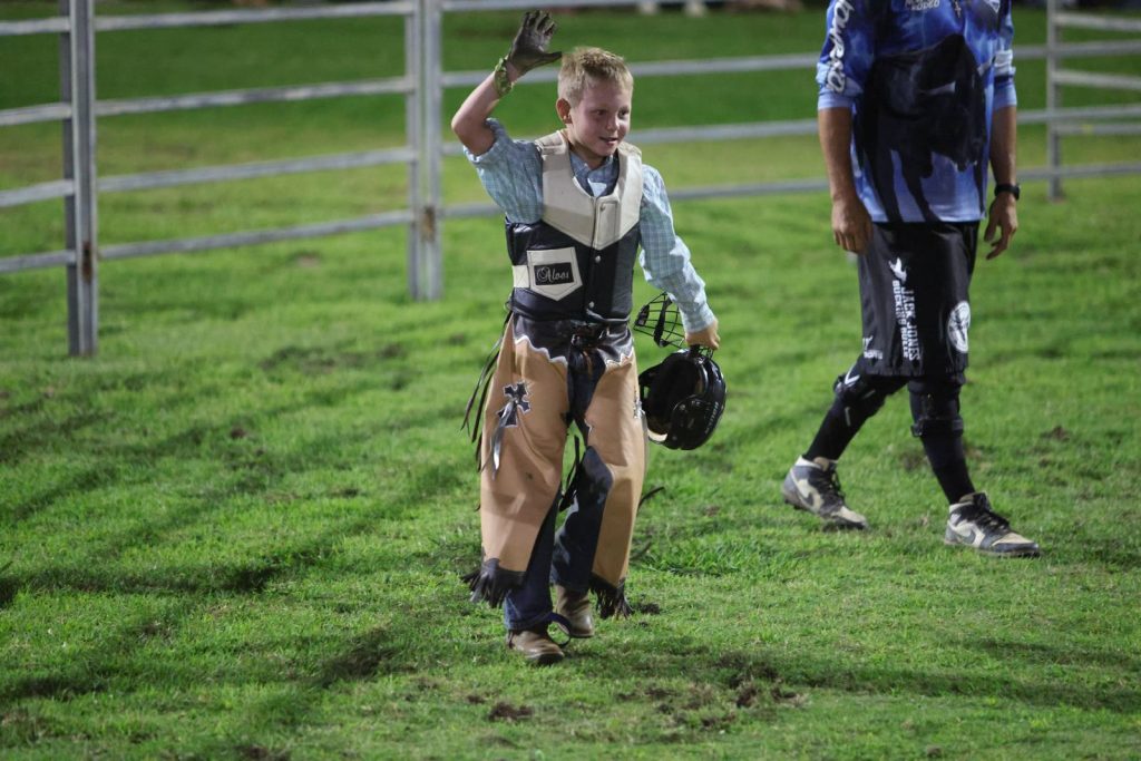 A young rider walking off after his ride