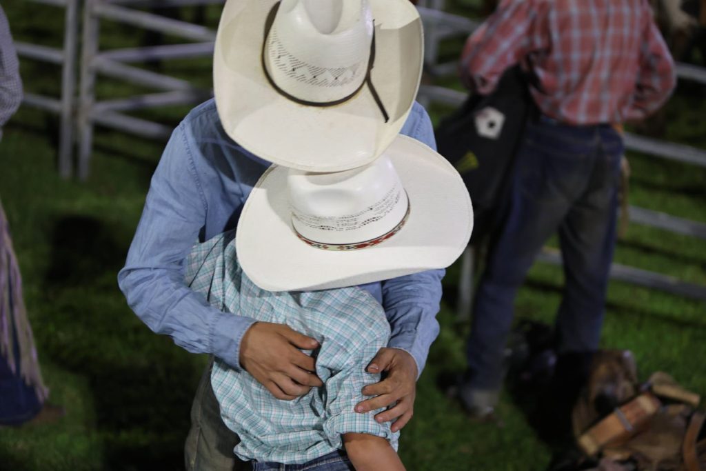 A cowboy carrying a small child