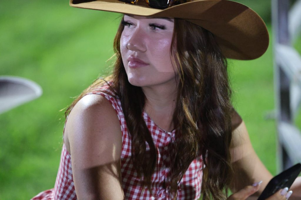 A young woman in a cowboy hat watching the rodeo
