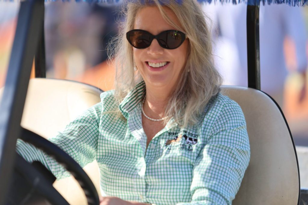 A volunteer smiling at the wheel of a golf buggy