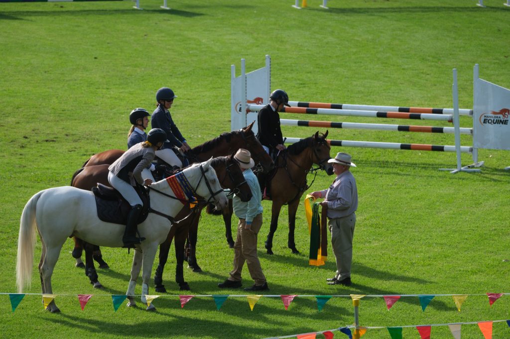 Young riders on ponies waiting by the showjumping course