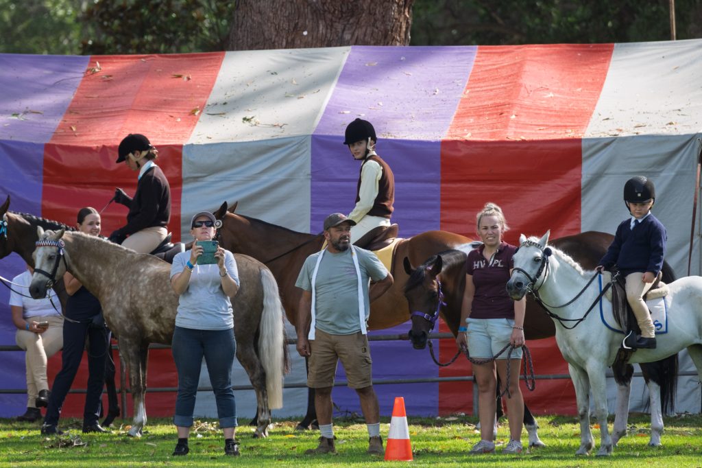 Junior riders and their ponies in front of a striped marquee
