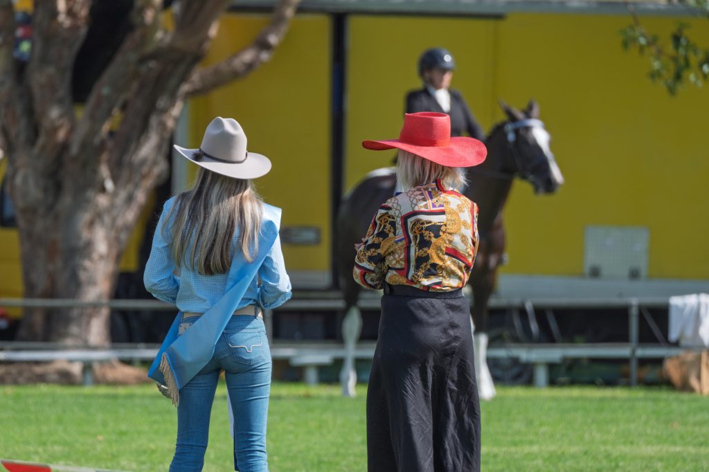 Two women in western hats watching the ring