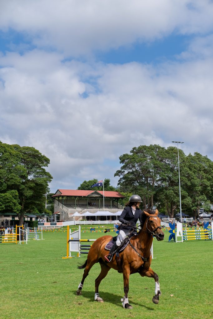 A rider cantering across the showjumping ring
