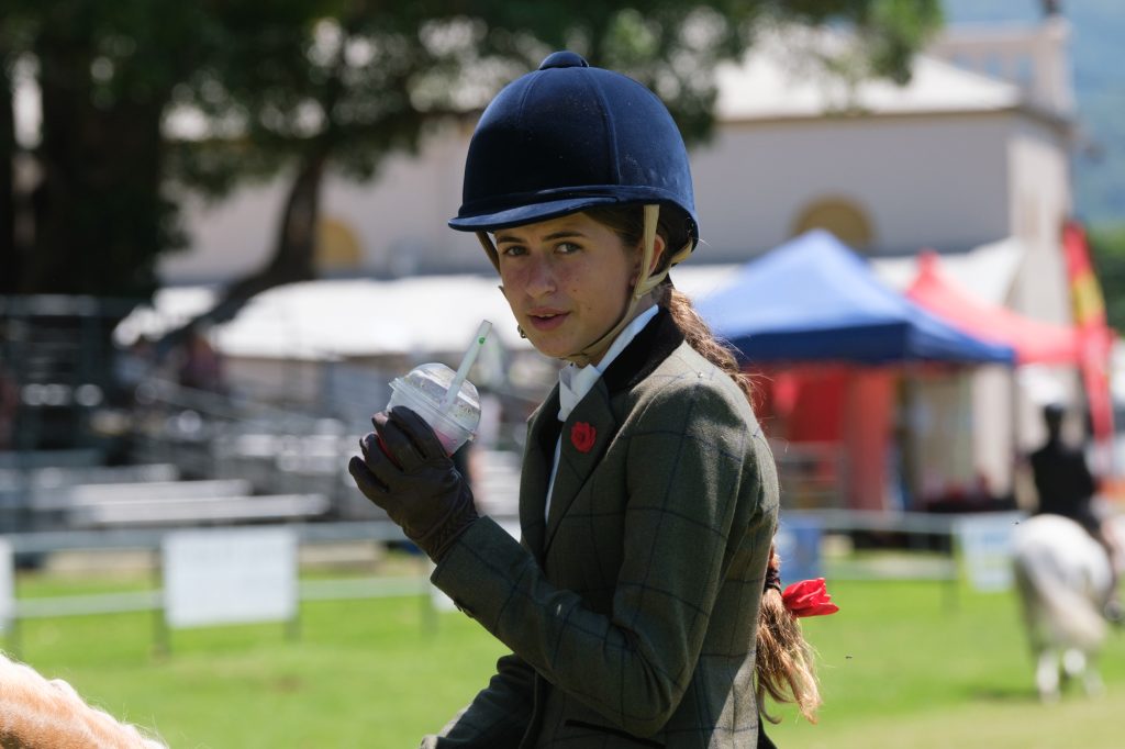A young rider in a velvet helmet, drink in hand