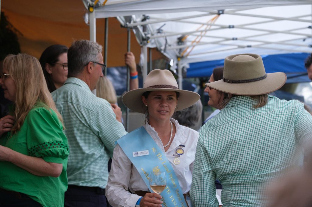 Visitors talking with a Young Woman entrant in her sash