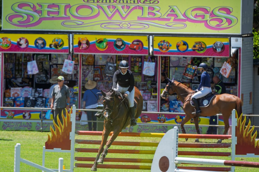 Riders jumping in front of the showbags stall