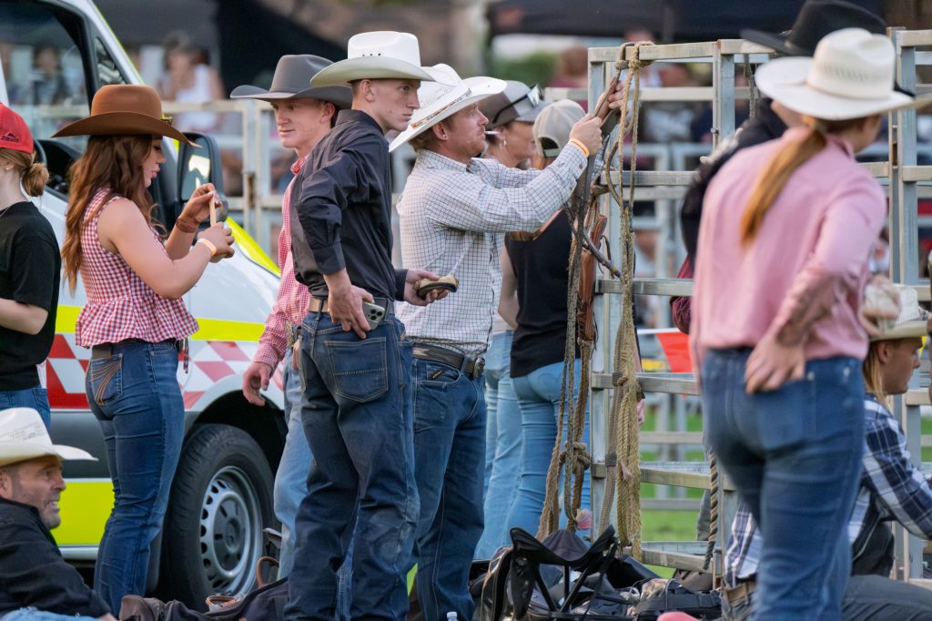 Cowboys watching from behind the rodeo chutes