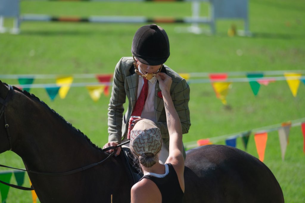A young rider reaching up to her horse