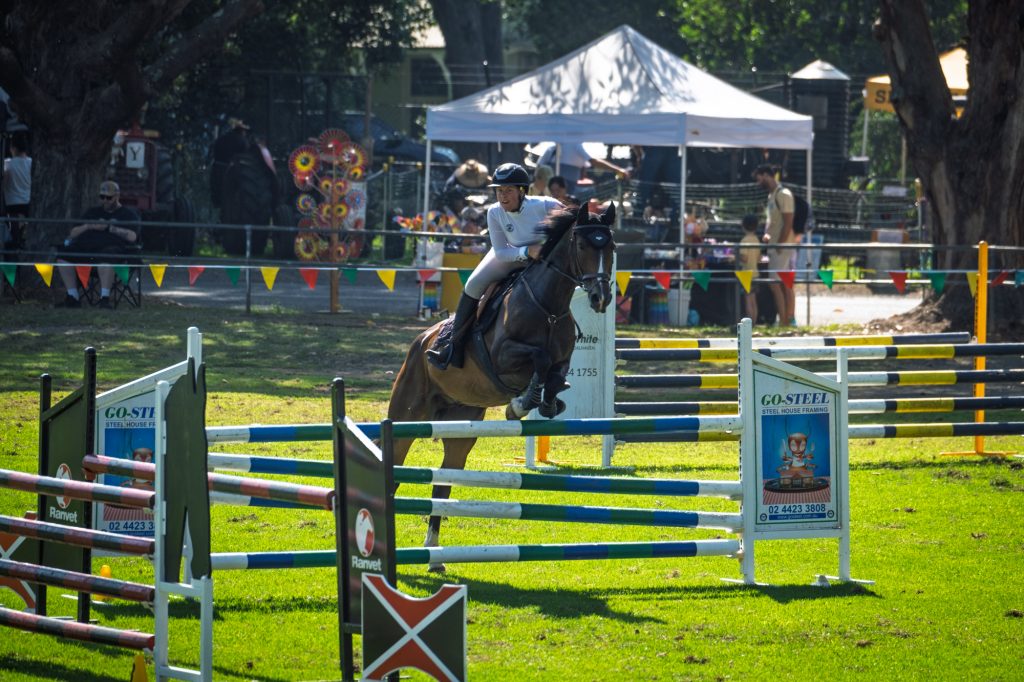 A horse and rider over a jump beside the marquees