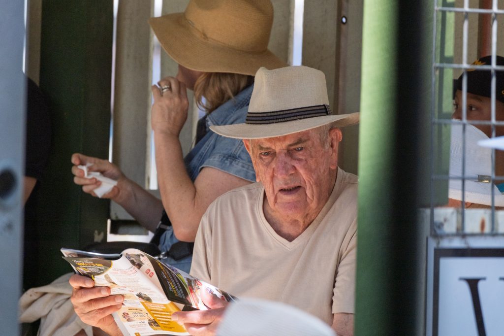 An older man reading the program under his hat
