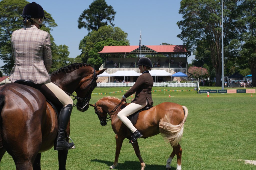 Two riders side by side in front of the grandstand