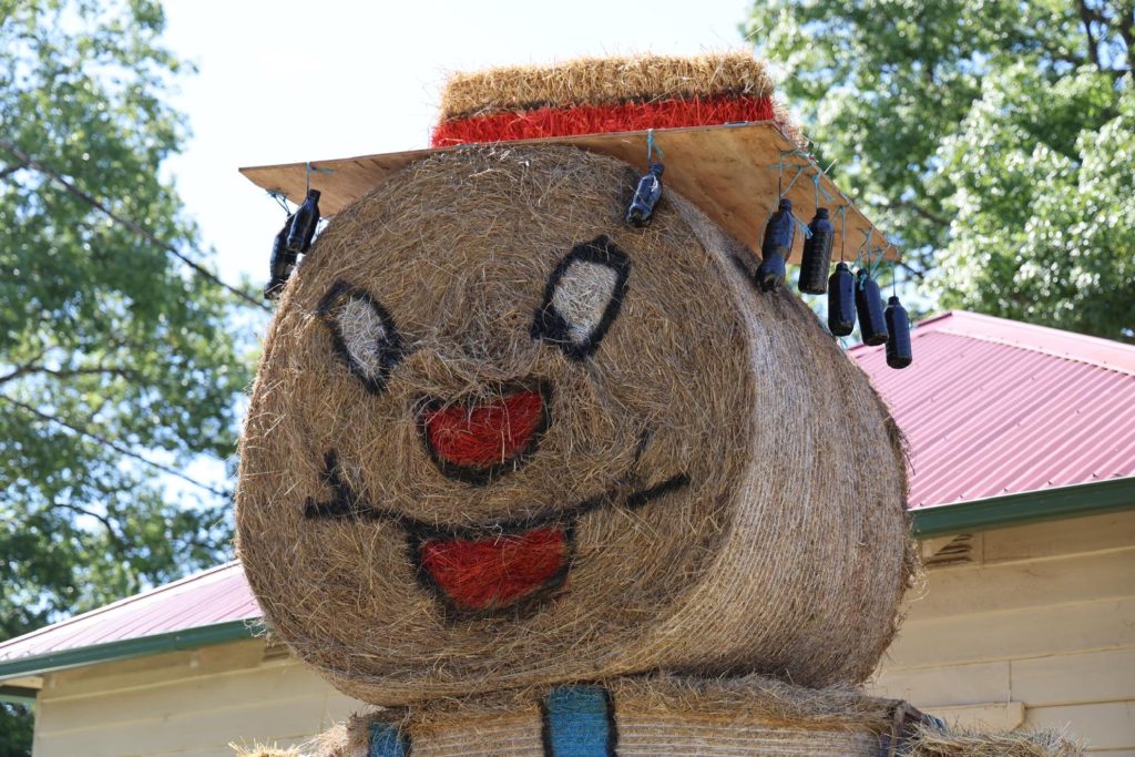 A hay bale dressed up with a face and hat