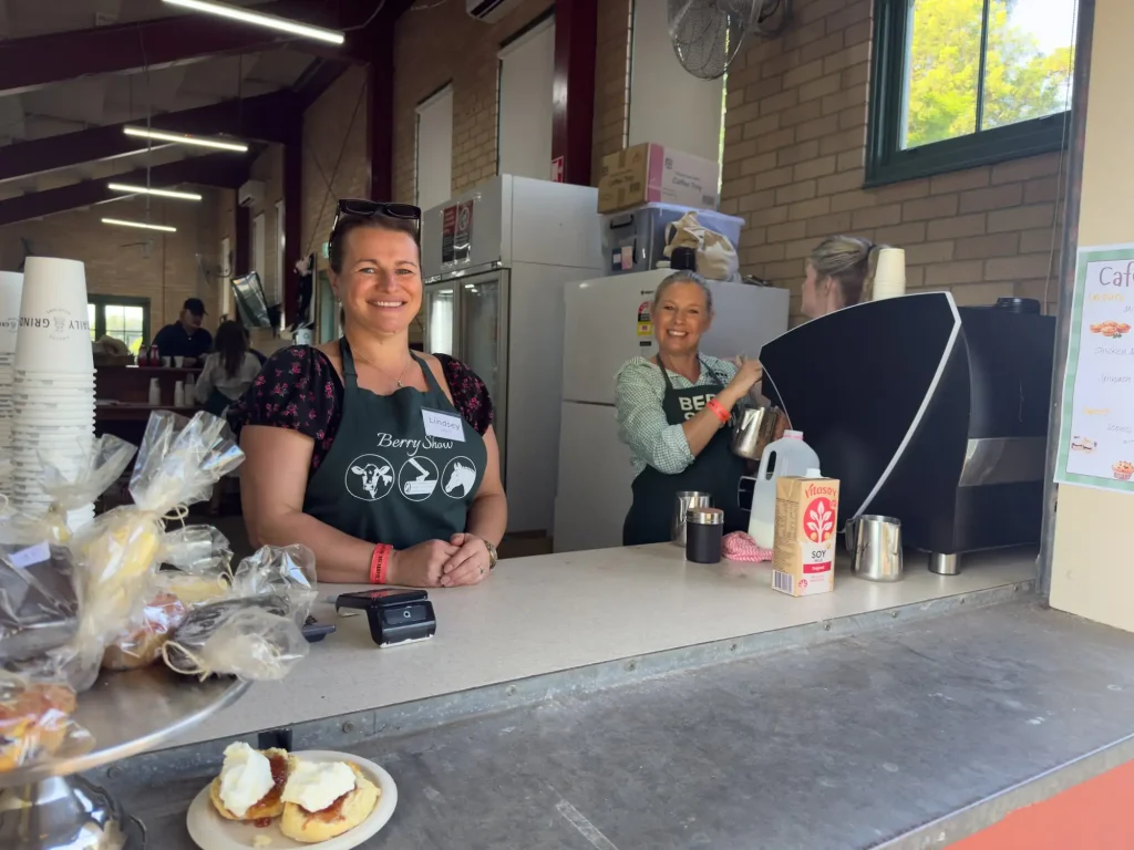 Smiling volunteers in Berry Show aprons behind the Grandstand Café counter