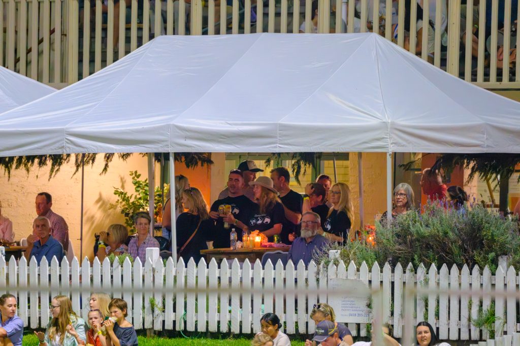 Sponsors at tables under the white marquee in the VIP area