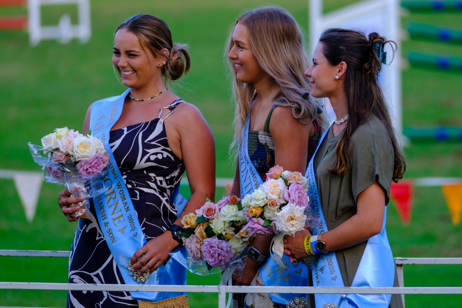 Three Berry Show Young Woman entrants in sashes holding bouquets by the ring